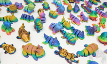 Load image into Gallery viewer, Multiple 3D printed fidget animals in vibrant rainbow colors, featuring different designs like dinosaurs, owls, and sharks, displayed on a flat surface.