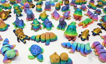 Load image into Gallery viewer, A collection of colorful 3D printed fidget animals in Silk Rainbow, Gloss Rainbow, and Matte Rainbow finishes, arranged on a white background. Includes various articulated designs such as unicorns, dragons, and caterpillars.