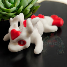 Load image into Gallery viewer, Valentine Love Dragon mini articulated figure with a white body and red heart accents, displayed on a sleek black surface next to a green succulent. The figure features smooth joints, making it perfect for stress relief, fidgeting, or as a decorative Valentine's Day gift. Photographed with the Convixxion logo subtly in the background.