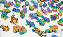 Load image into Gallery viewer, Multiple 3D printed fidget animals in vibrant rainbow colors, featuring different designs like dinosaurs, owls, and sharks, displayed on a flat surface.
