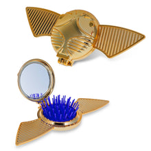 Load image into Gallery viewer, Harry Potter Golden Snitch pop-up brush and mirror set by Mad Beauty, shown twice on a white background, with one view of the closed gold winged compact and one view opened to reveal a round mirror and blue bristle hair brush.
