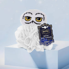 Load image into Gallery viewer, Harry Potter Hedwig body exfoliator pouf by Mad Beauty, featuring a white bath pouf with an embroidered Hedwig owl face topper and blue hang tag, displayed on a light blue block with a soft blue background.
