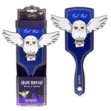 Load image into Gallery viewer, Harry Potter Hedwig “Owl Post” hair brush by Mad Beauty, shown upright in purple packaging on the left and separately on the right, featuring Hedwig with outstretched wings holding a Hogwarts letter on a white background.
