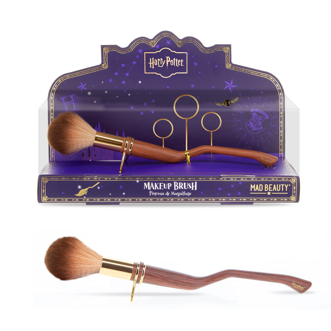 Harry Potter Mad Beauty makeup brush with soft brown bristles and a curved broomstick-style wooden handle shown once in purple Quidditch-themed display packaging and once on its own against a white background.